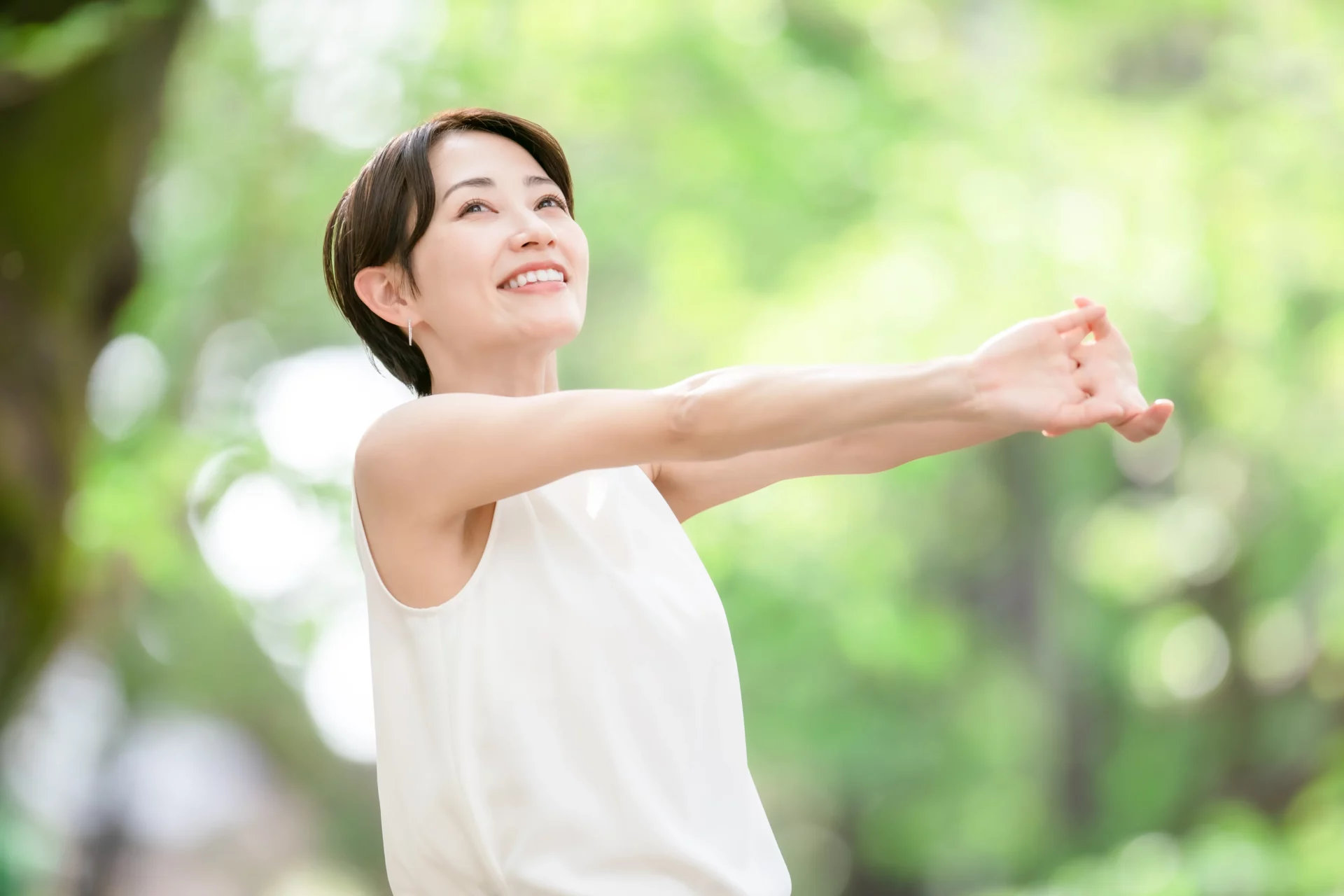 屋外で腕を伸ばしてストレッチをする女性